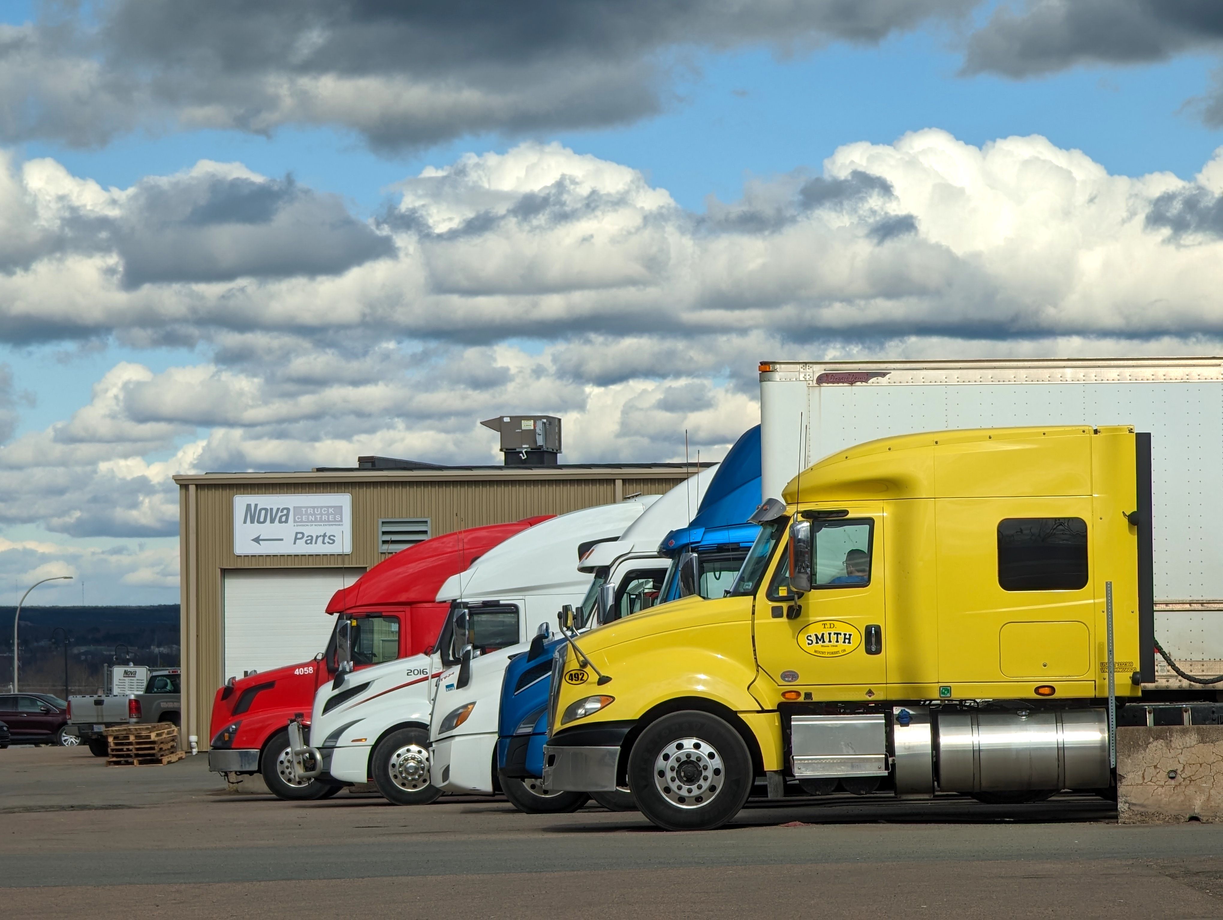 Row of tractor-trailers parked at a truck service center
