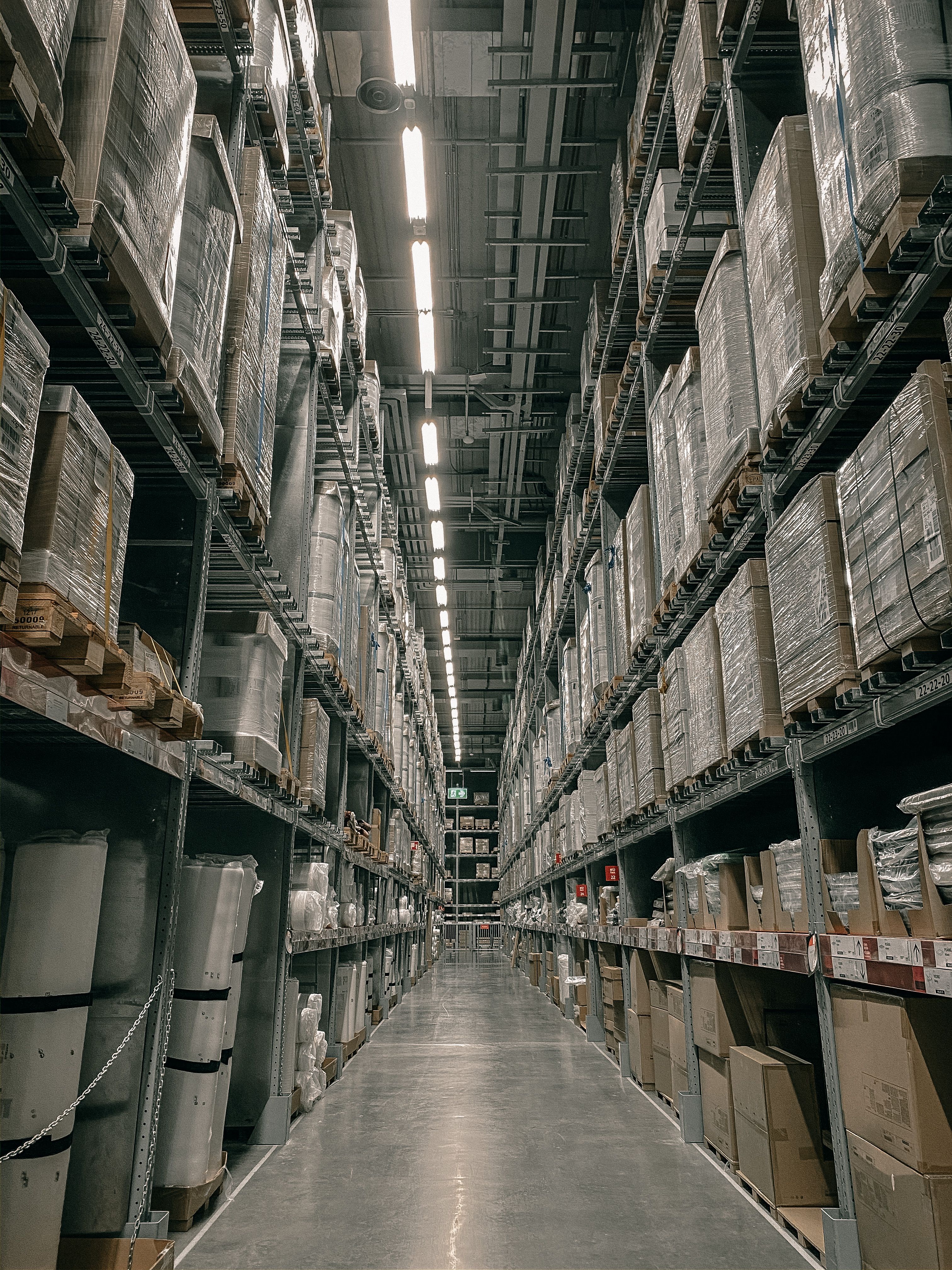 Tall warehouse racking aisle stacked with wrapped pallets