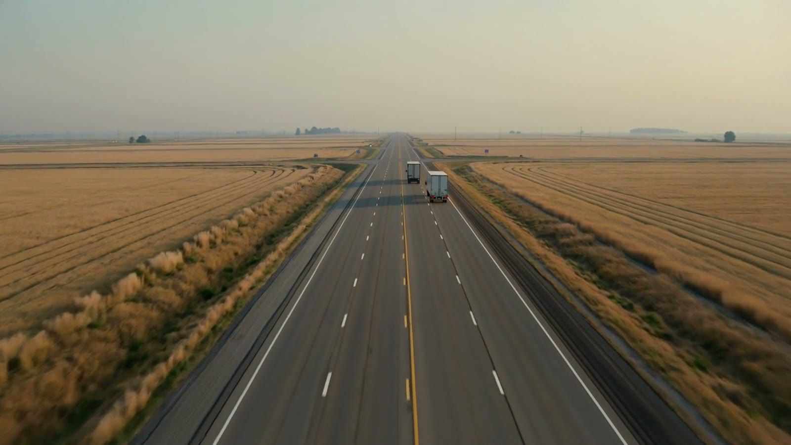 Tractor-trailers on a U.S. highway at dusk: the lanes a reliable freight broker quotes every day, pallet to full truck