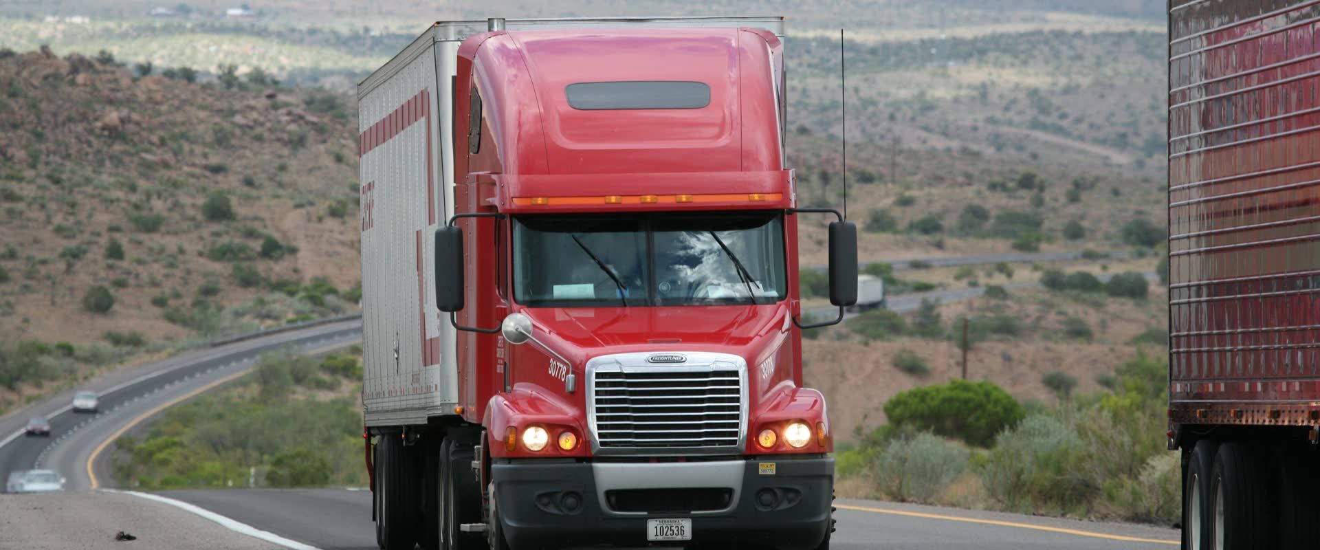 Red tractor-trailer on a highway, the freight a freight brokerage run by operators moves every day