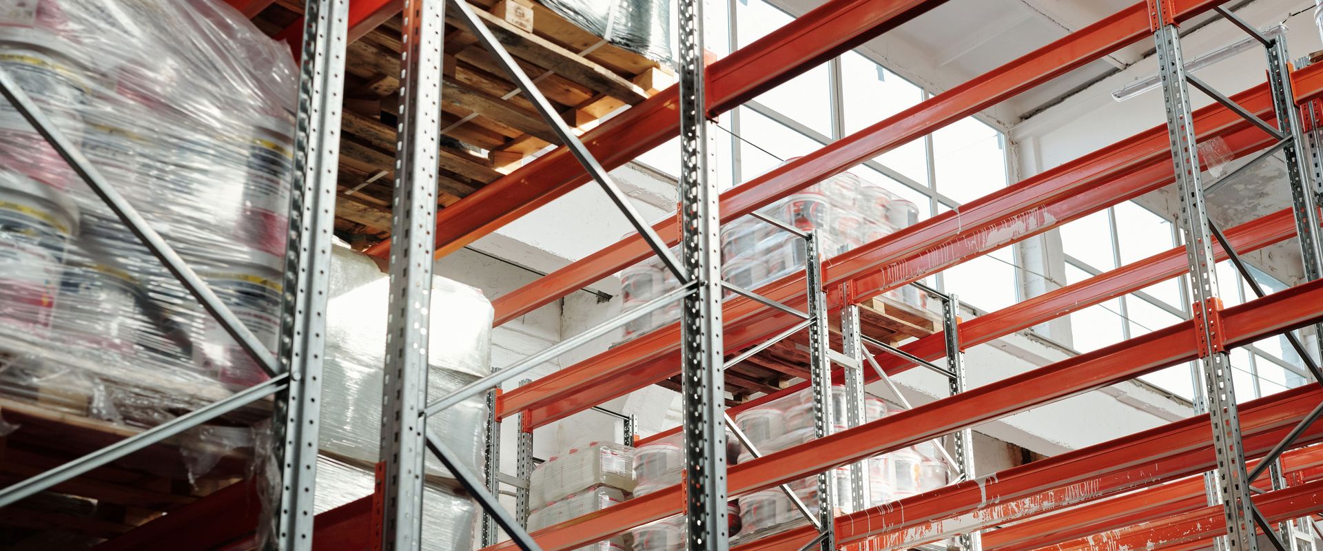 Shrink-wrapped pallets on warehouse racking: inspect the wrap and count the pieces before you sign, the first step in how to file a freight claim, including a concealed damage claim