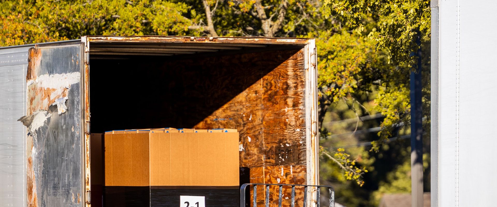 A shrink-wrapped pallet of cartons at the open door of a trailer: how to ship a pallet starts with palletizing freight square and tight