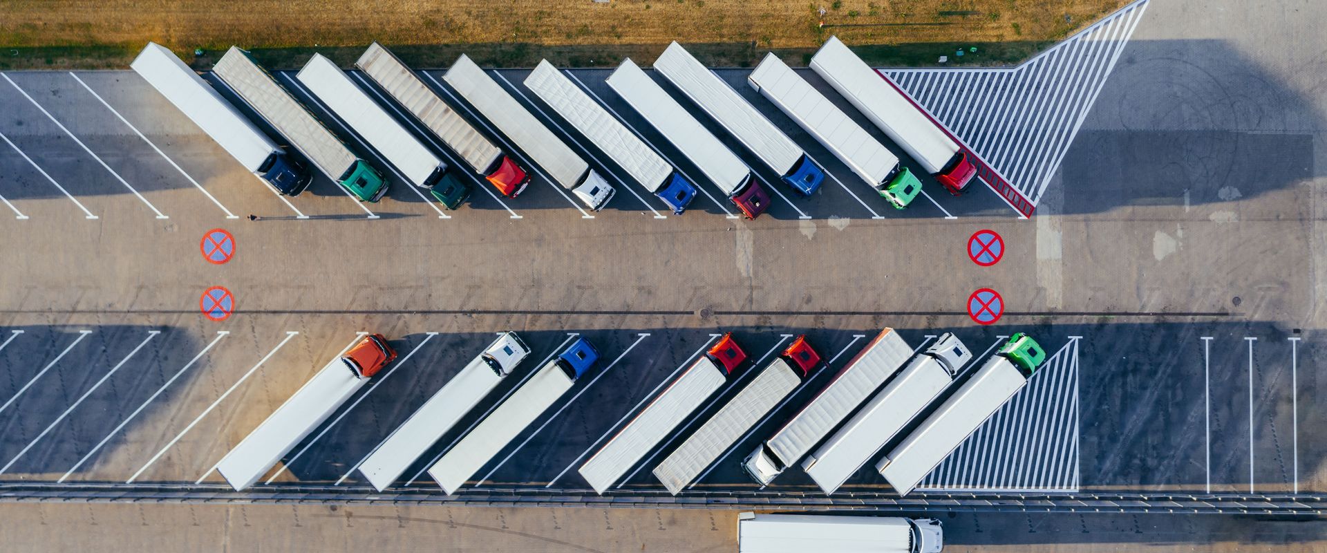 Aerial view of trailers parked in angled bays: LTL vs FTL is a question of how much of one trailer you fill, and volume LTL vs partial truckload is the in-between