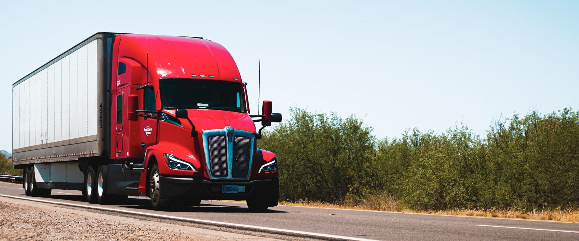 Red tractor-trailer on an open road: track an LTL shipment like this one by PRO number